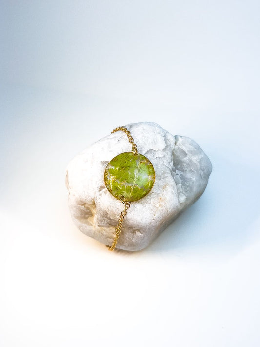 Round pendant bracelet made from pressed ferns in gold.