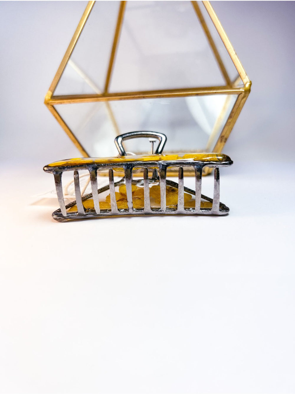 Bottom view of a silver hair claw made from pressed buttercups.