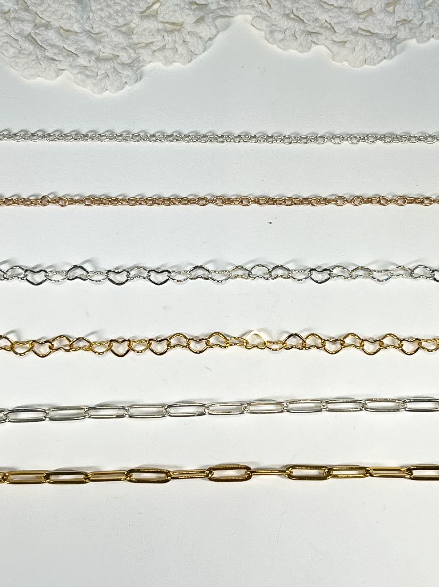 Chains for the custom charm bracelet bar. Plain chain, heart chain, & paperclip chain laid out in gold and silver.