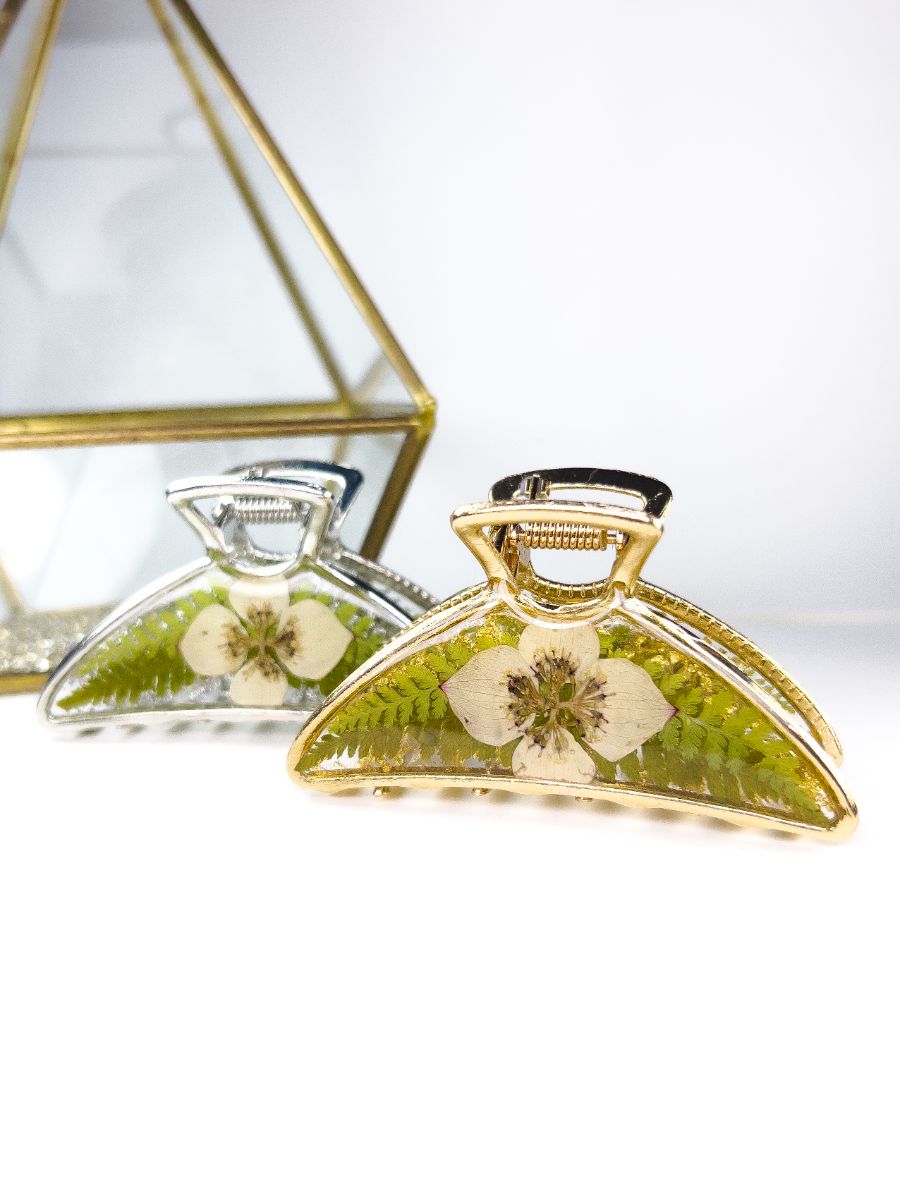 Two metal hair claws with pressed dogwood flowers and ferns. One clip is silver and one is gold.