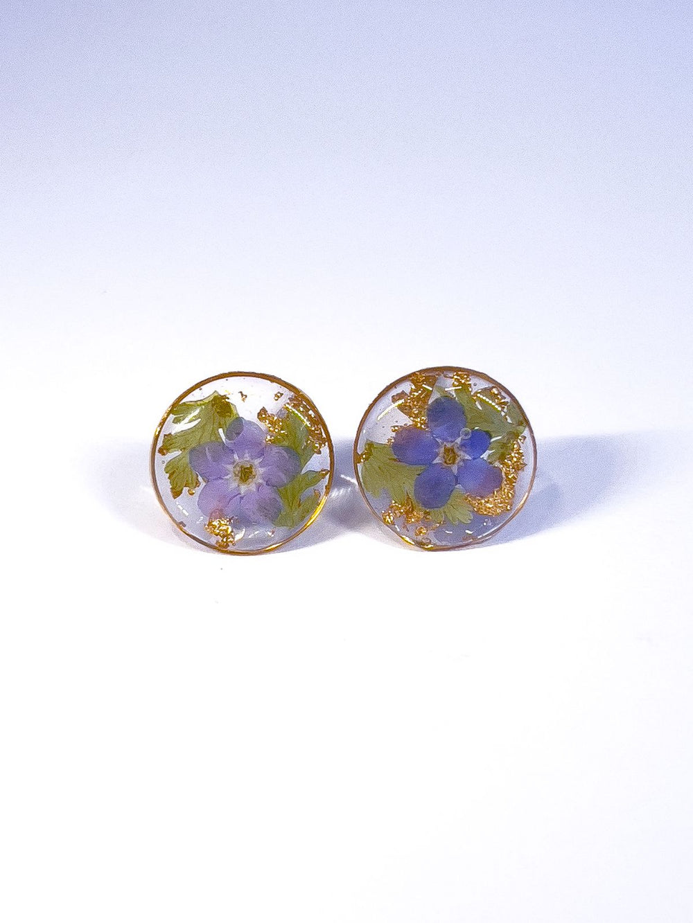 Round stud earrings made from pressed forget-me-not flowers and ferns. 