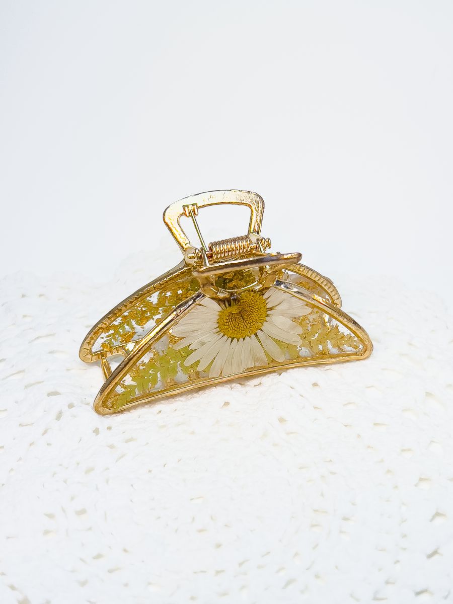 Top angle of metal hair clip made from daisy flowers and real fern.
