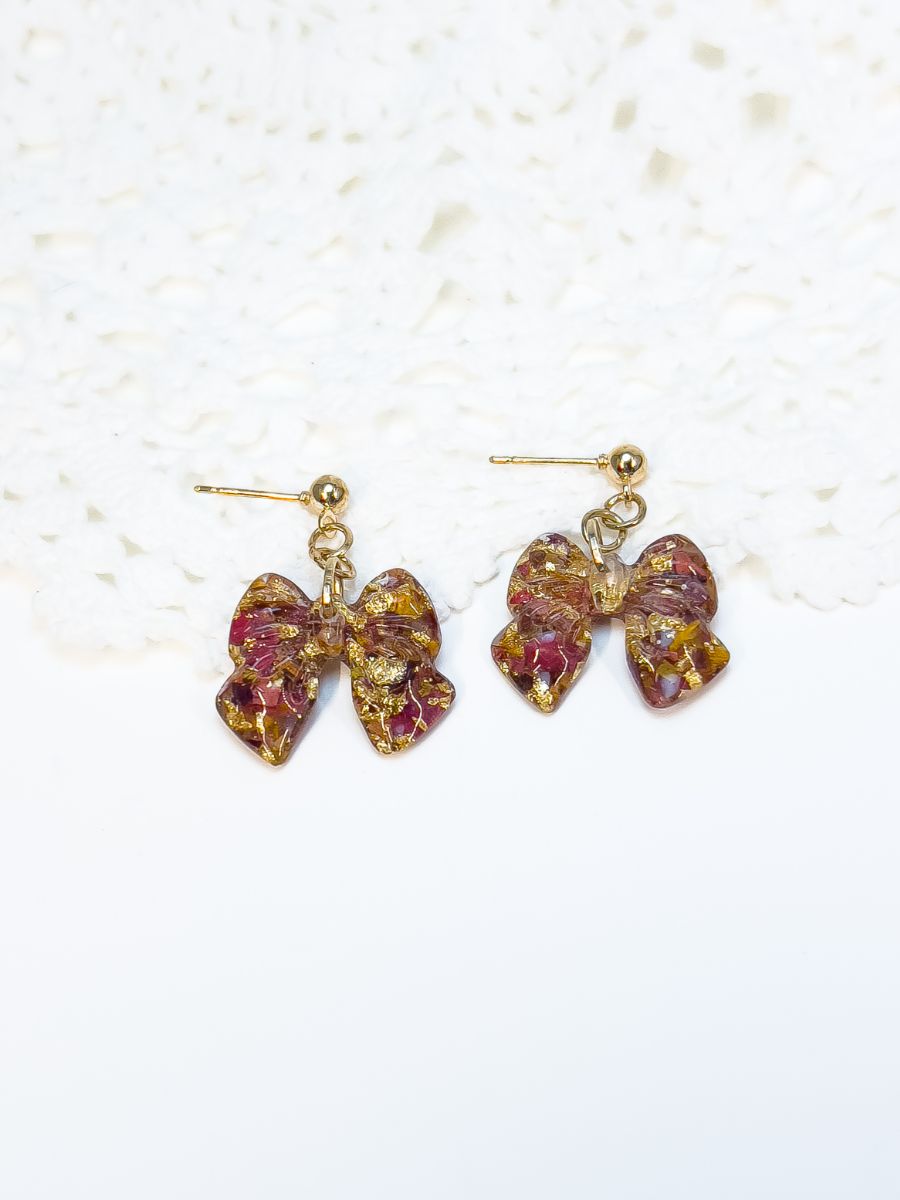 Crushed autumn maple leaves in a bow. They have a stud-style dangle. 