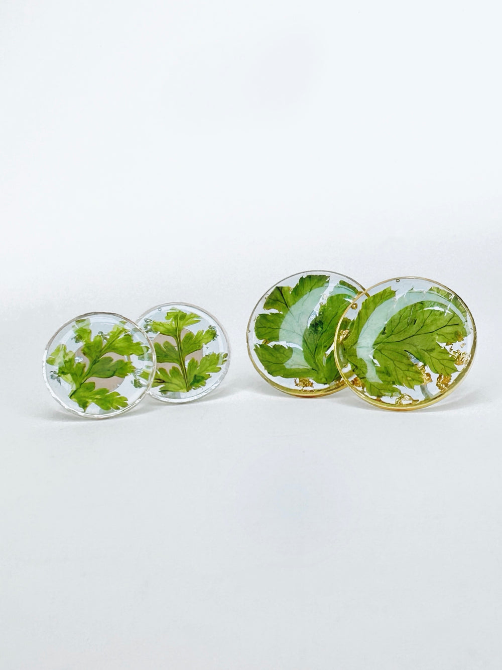 Round stud earrings made from pressed ferns. First pair is small size in silver. Second pair is medium size in gold. 