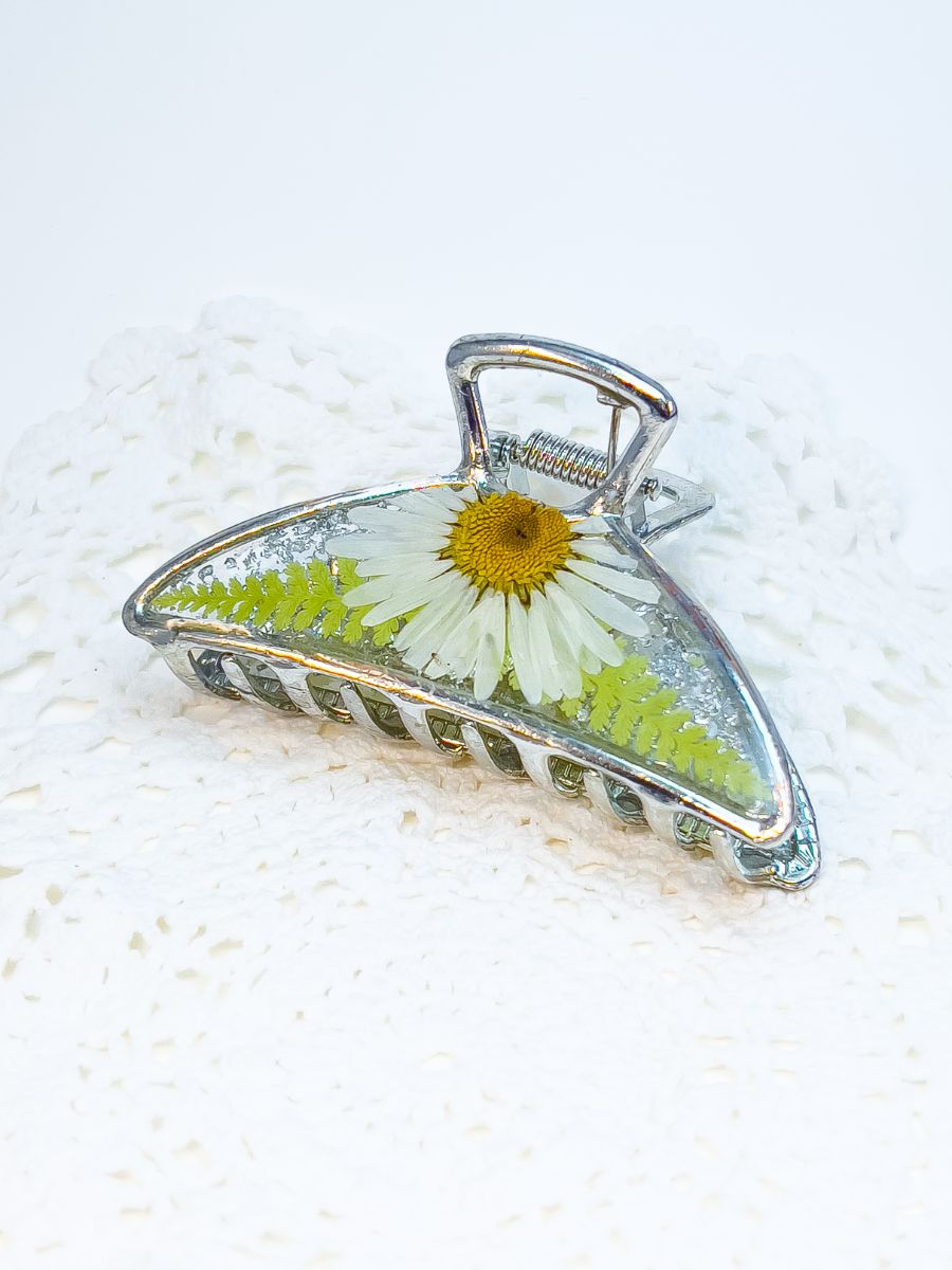 Top angle of silver metal hair claw made from real daisies and ferns.